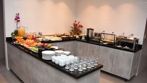 Una mesa de buffet con diversos alimentos, platos y vasos.