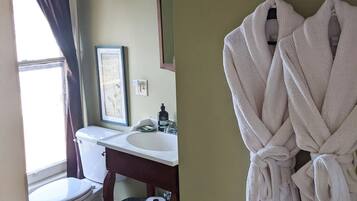 A bathroom with a toilet, sink, and a robe hanging on a rack.