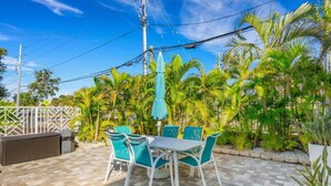 A patio with a table and chairs, surrounded by palm trees and a fence. - 🌴 Tranquil Coastal Escape @ Clearwater Beach Suites | Steps to Sand • Heated Pool ➠ CBS 203 (Clearwater)