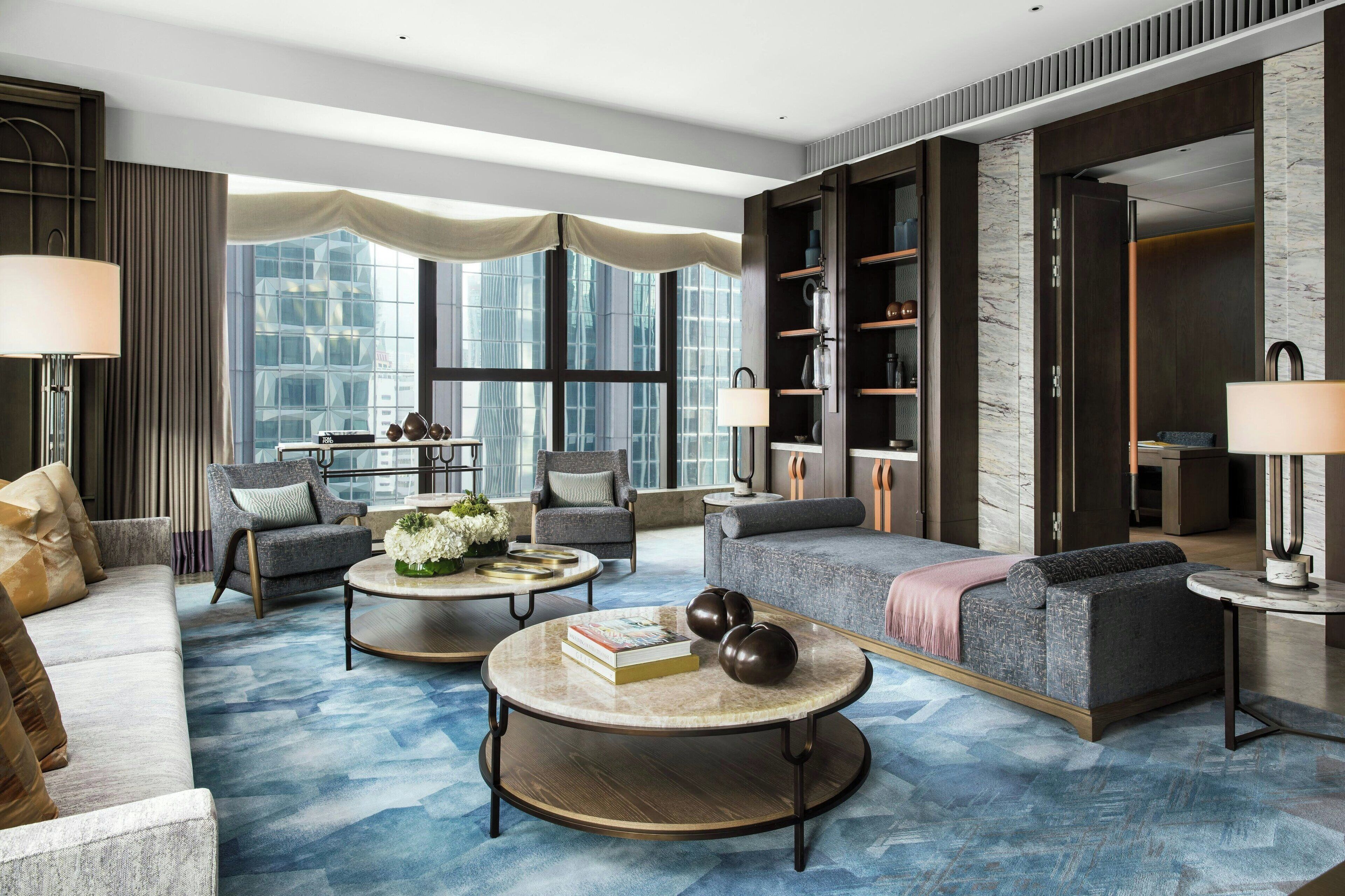 A modern living room with a sofa, armchairs, a coffee table, and a bookshelf.