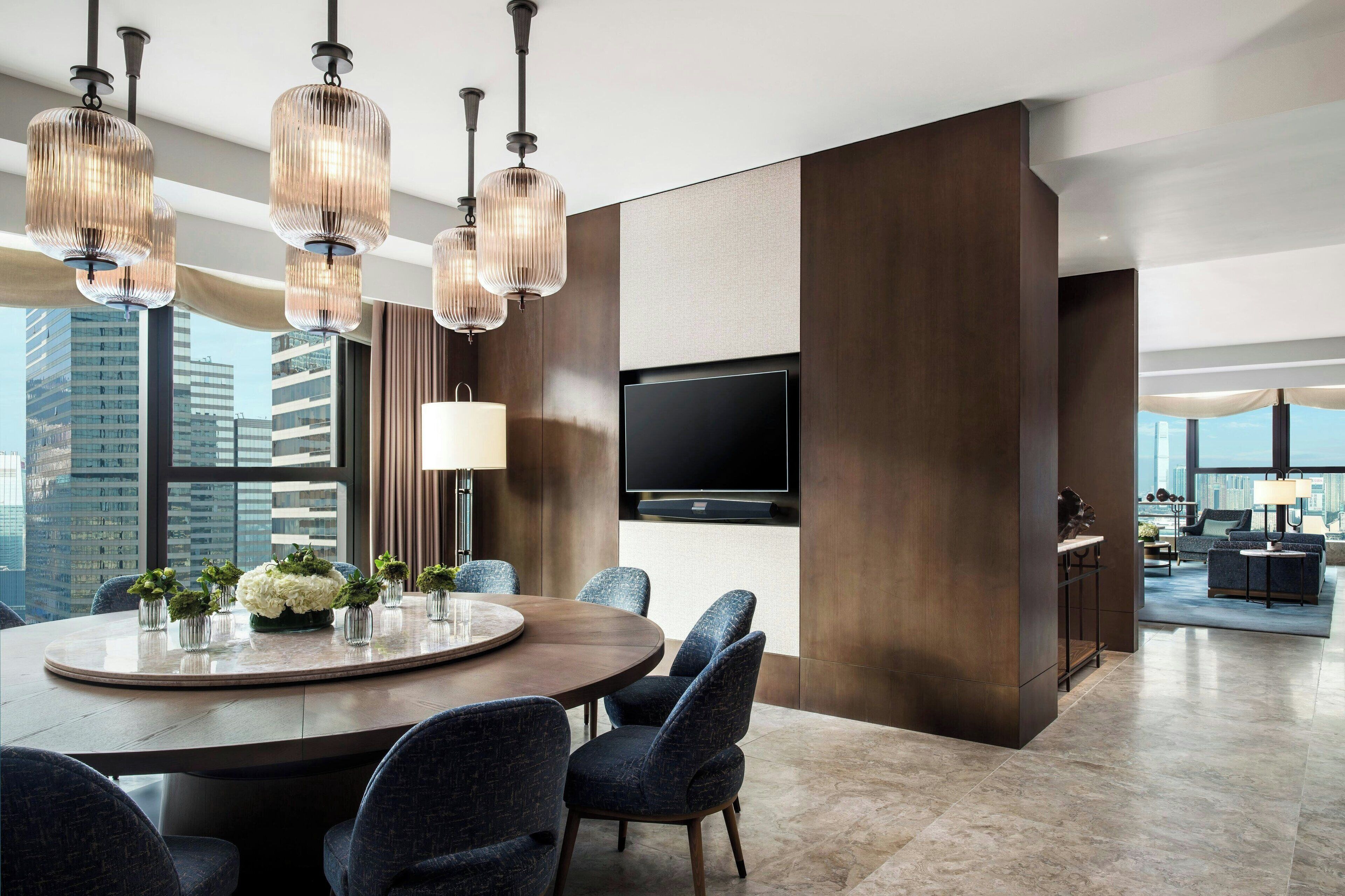 A modern dining area with a round table, blue upholstered chairs, and pendant lighting.