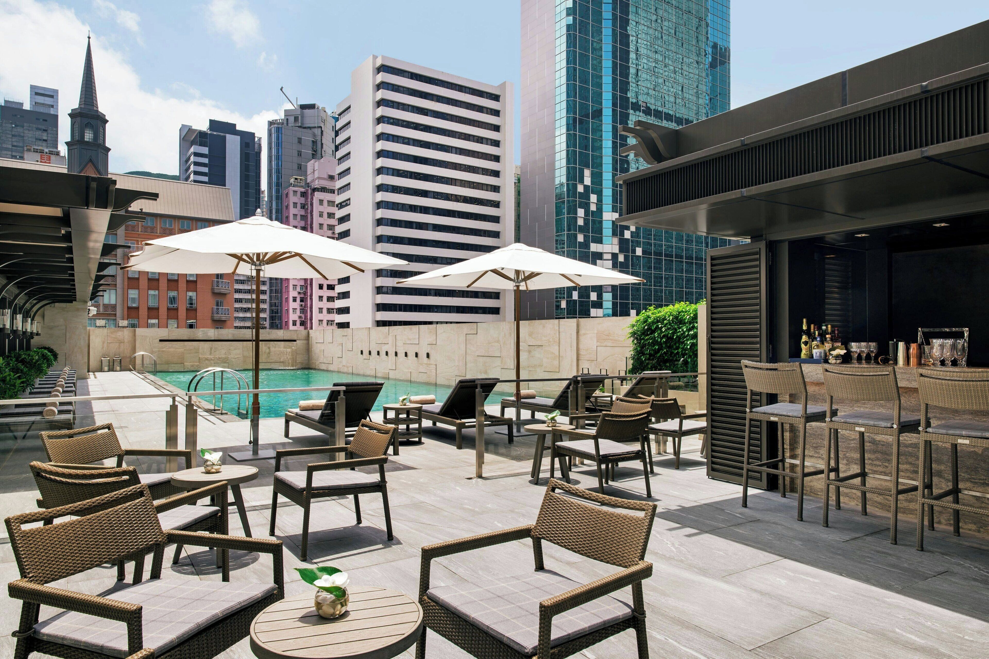 A rooftop bar with outdoor seating, a pool, and city views.