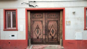 A building with a red and white facade, featuring a large, ornate double door with the inscription "1916". - Quinta in Aveiro Casa 3 Águias - Suite (Aveiro)