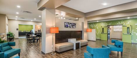 A spacious lobby with a reception desk, seating area, and a kitchenette in the background.