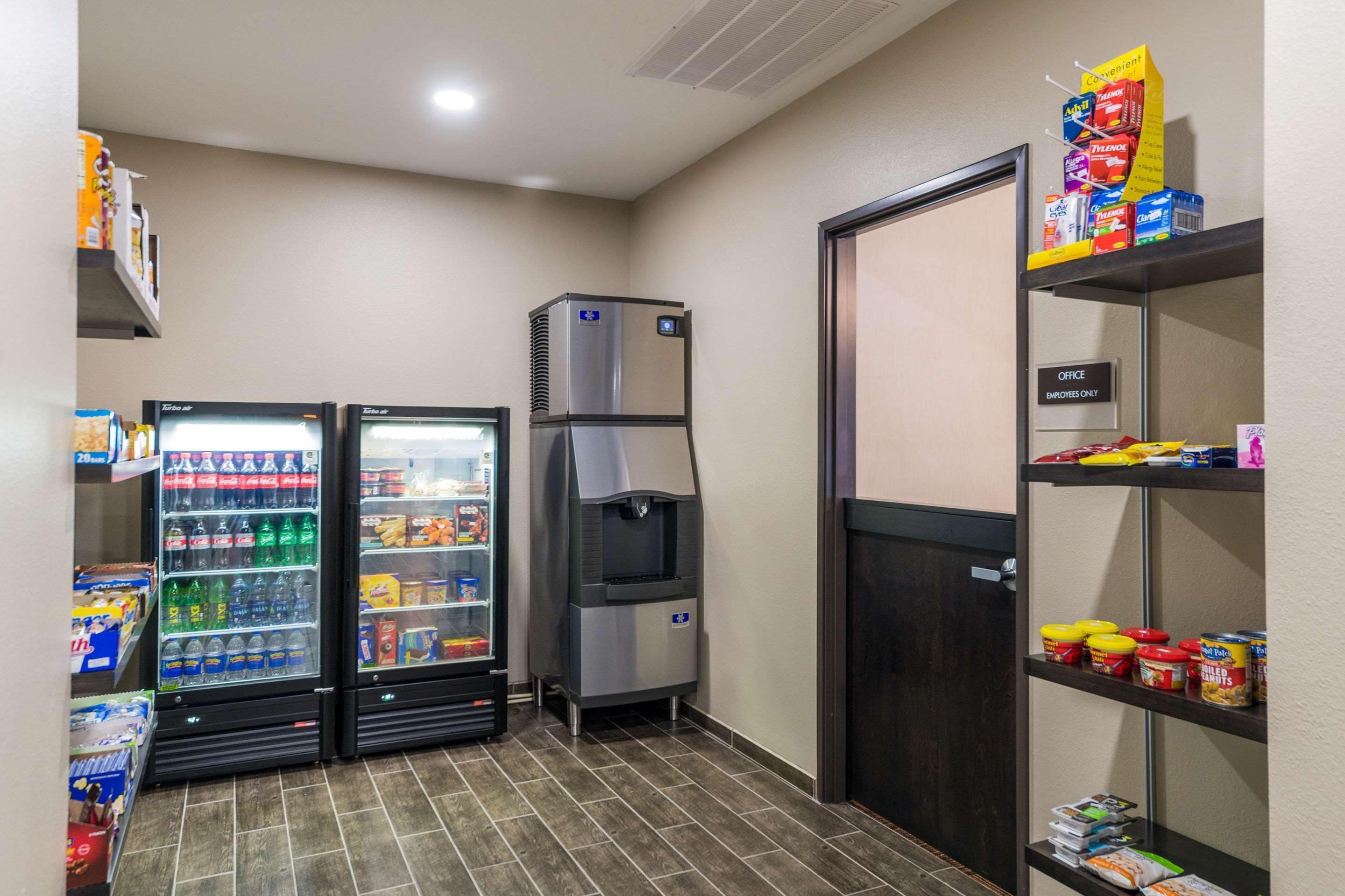 A kitchenette area with a refrigerator, a water cooler, and shelves stocked with snacks and beverages.