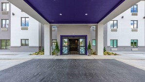 Una entrada moderna a un edificio con techo plano, ventanas amplias y una puerta central.