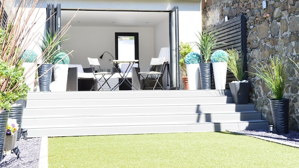 A modern outdoor patio with a seating area, steps leading up to a door, and potted plants. - Pier39Portrush (Portrush)