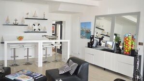 A modern kitchen with white cabinetry, a central island with bar stools, and nautical-themed decor. - Pier39Portrush (Portrush)