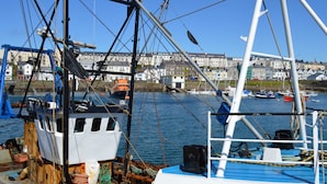 A harbor with boats docked, a crane, and buildings in the background. - Pier39Portrush (Portrush)
