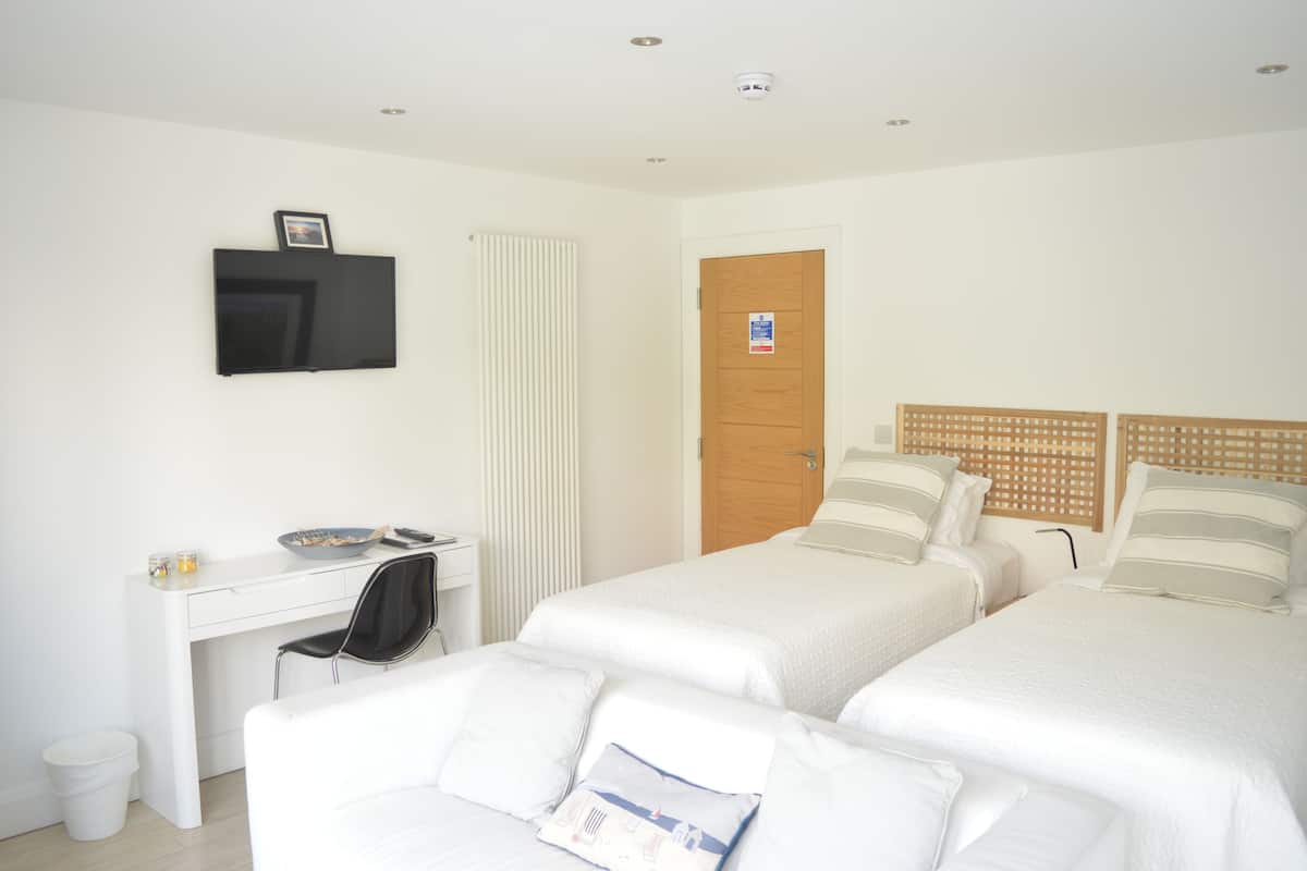 Une chambre d’hôtel avec deux lits, un bureau, une chaise, une télévision et une porte avec une pancarte.