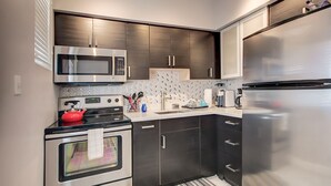 A modern kitchen with stainless steel appliances, dark cabinetry, and a tiled backsplash.