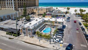 A hotel with a swimming pool, beachfront view, and parking area.