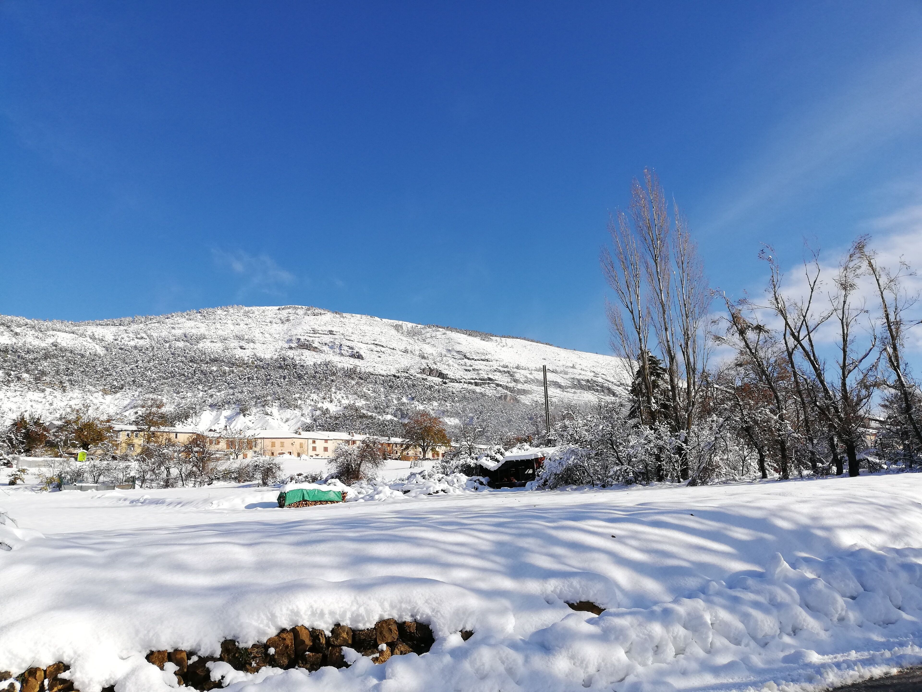 Schneebedeckte Landschaft mit einem Gebäude im Hintergrund.