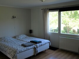 A bedroom with a bed, a window, a radiator, and a wall-mounted lamp.