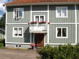 A two-story house with a balcony, a front door, and a small porch area.