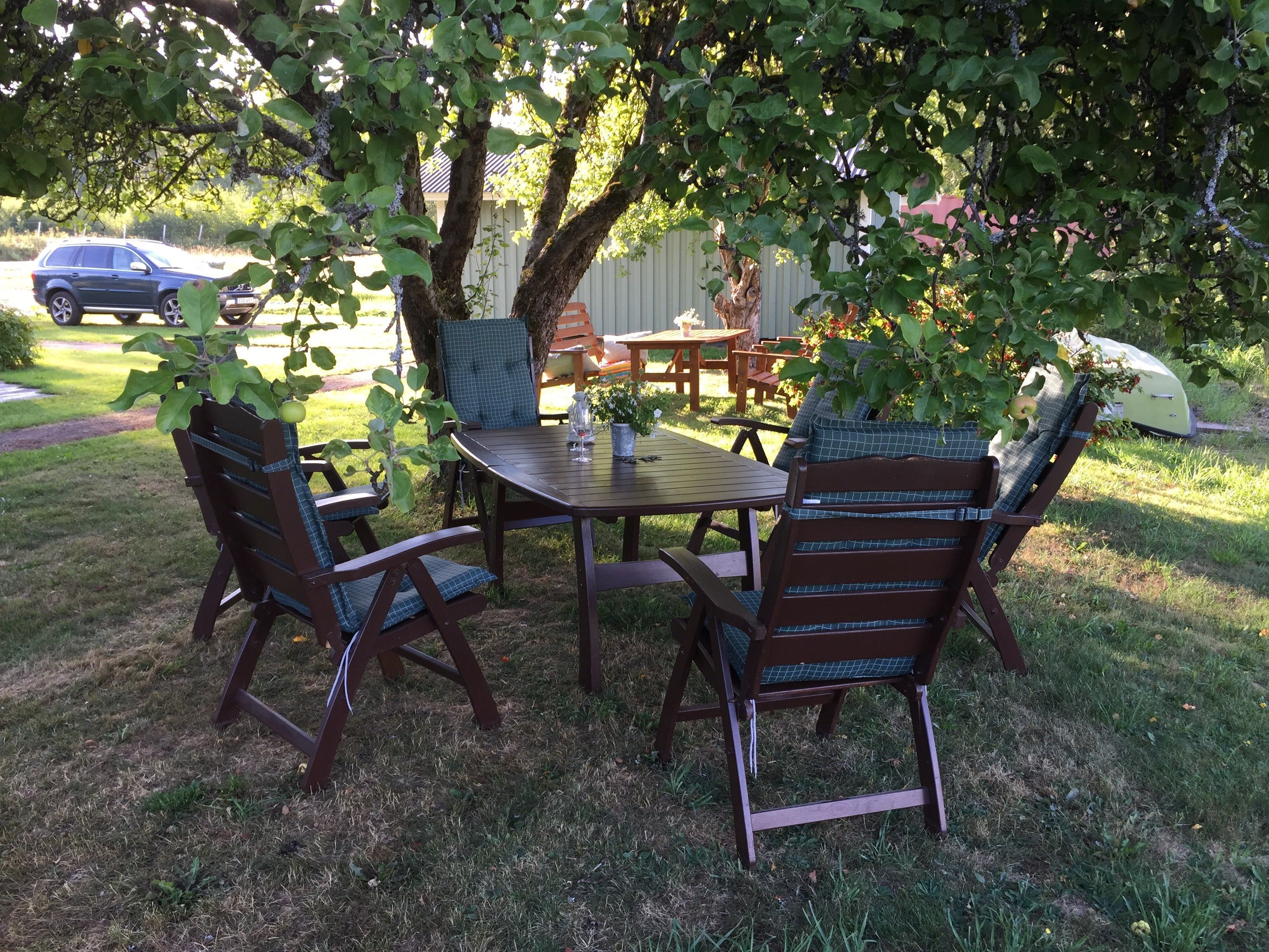 A patio with a table and chairs, surrounded by trees and a fence.
