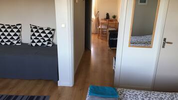 A room with a bed, a sofa, a small table, and a door.