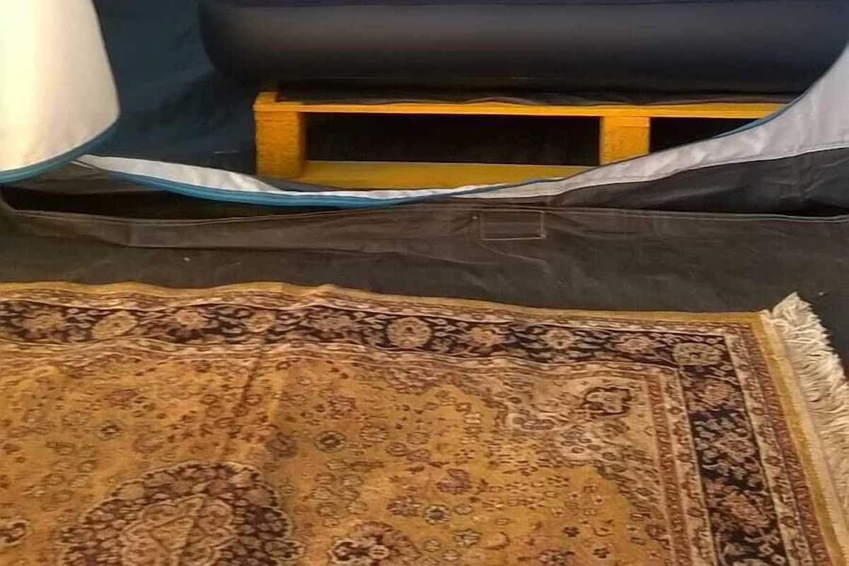 A tent with a bed inside, a small table, and a rug on the floor.