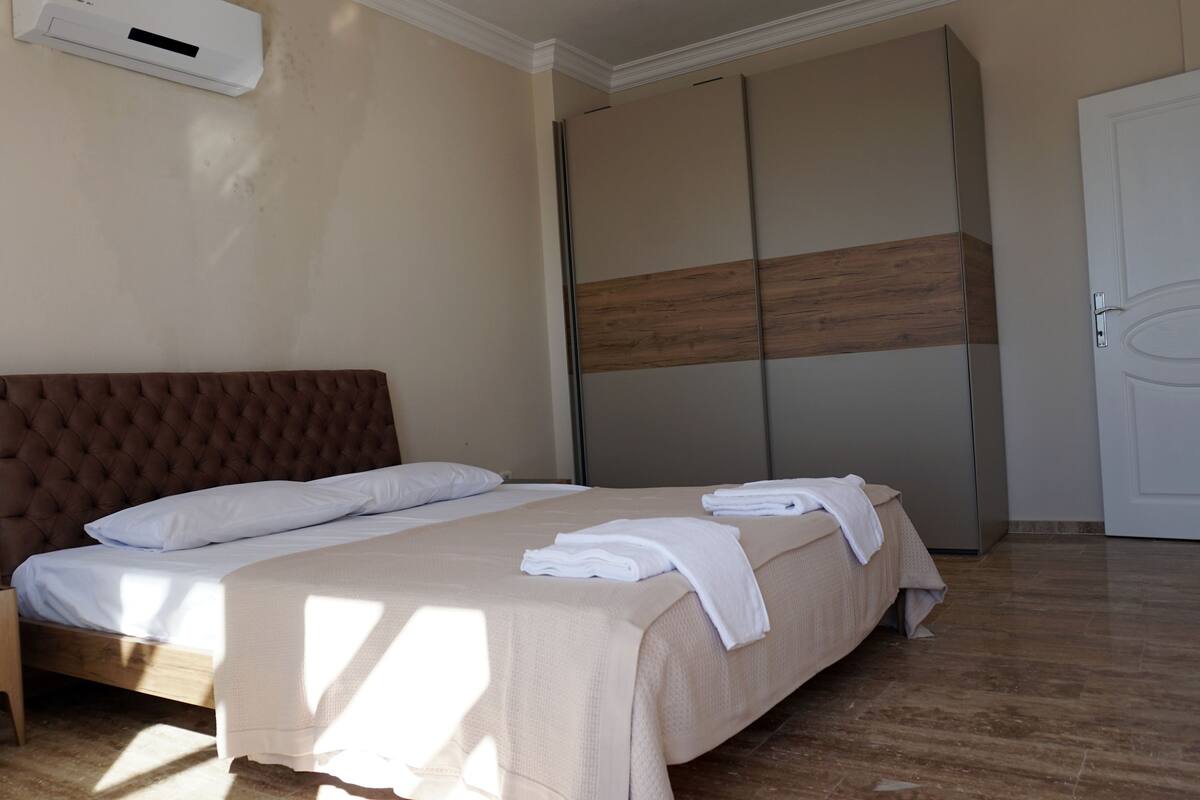 A bedroom with a bed, a nightstand, a wardrobe, and a door.