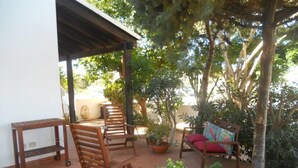 An outdoor patio with wooden furniture, including chairs and a table, surrounded by potted plants and trees. - VILLETTA MAGNOLIE in residence 400 mt from the sea, wi-fi free parking space. (San Vito Lo Capo)