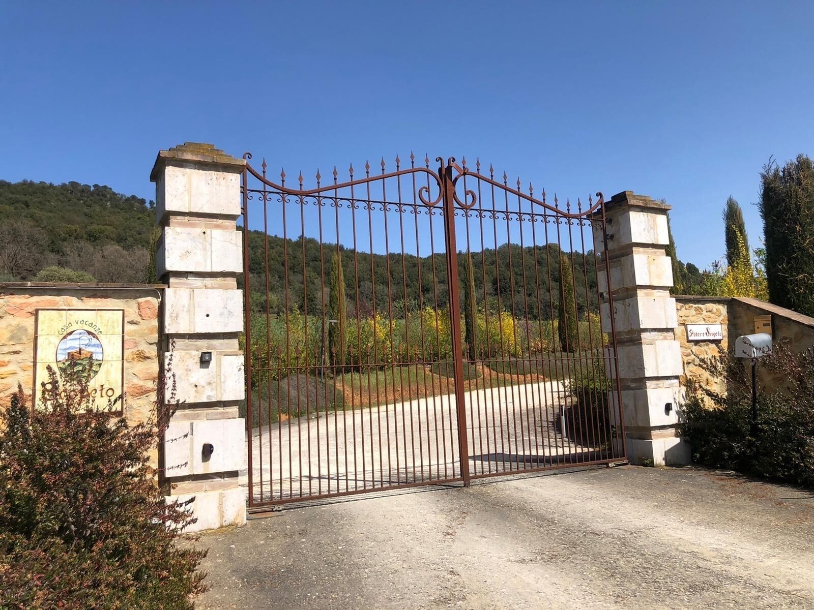 A gated entrance with a stone wall and a metal gate.