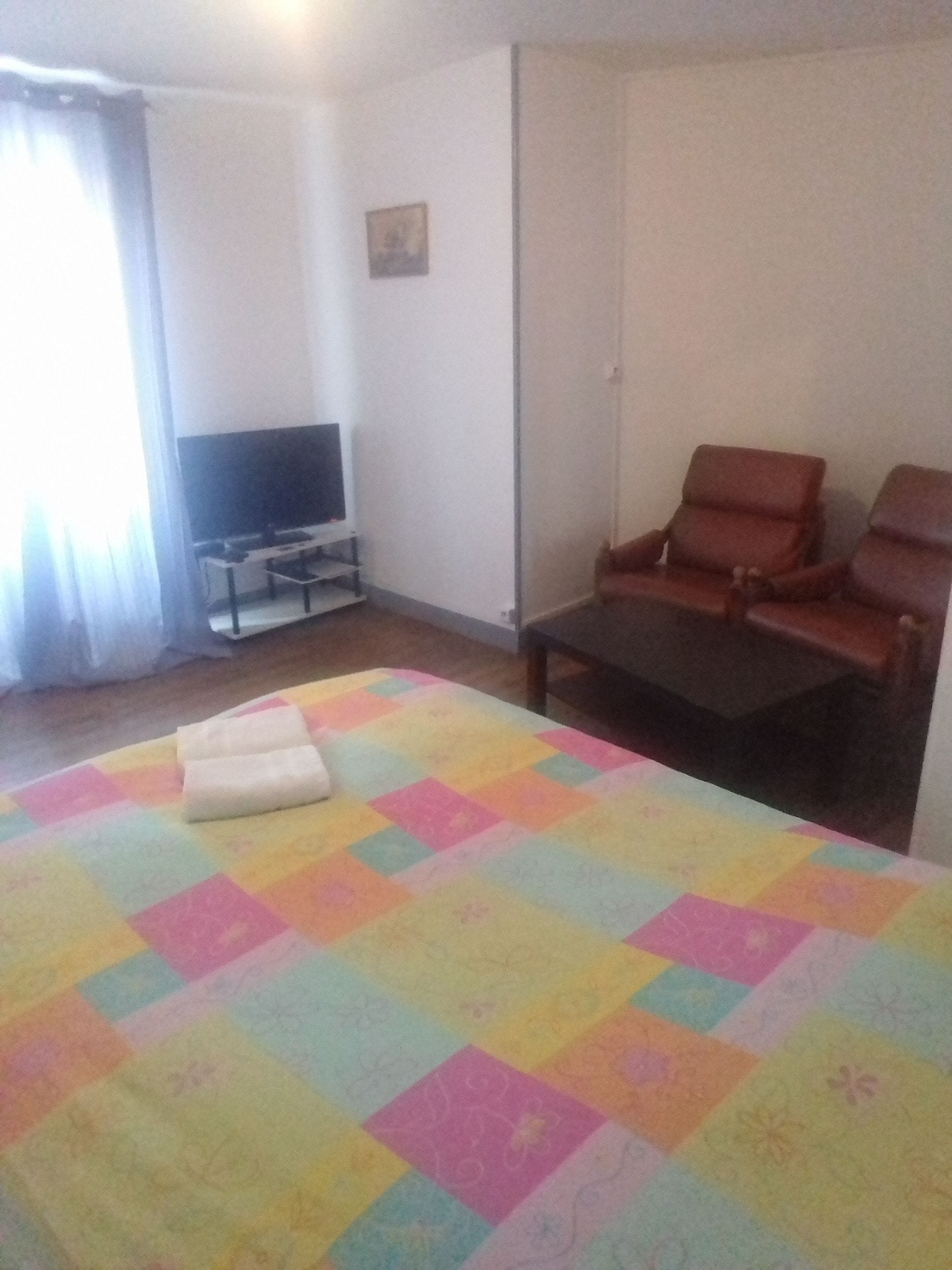 A hotel room with a bed, a television, a chair, and a small table.