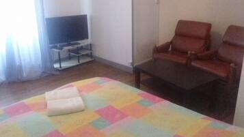 A hotel room with a bed, a television, a chair, and a small table.