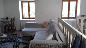 A cozy room with a sofa, a small table, and two windows. - Le Trois Mâts (Thiers)