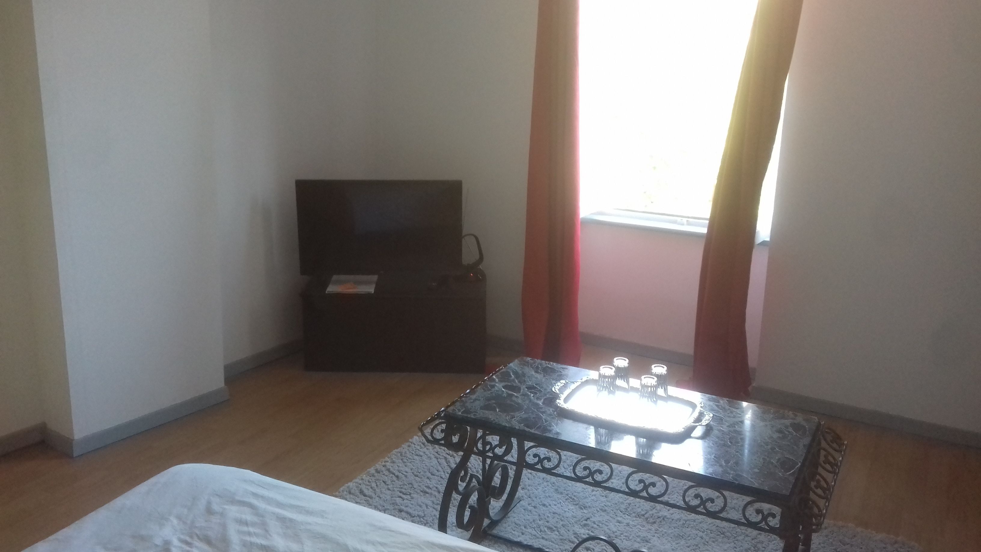A small room with a bed, a table, and a TV.