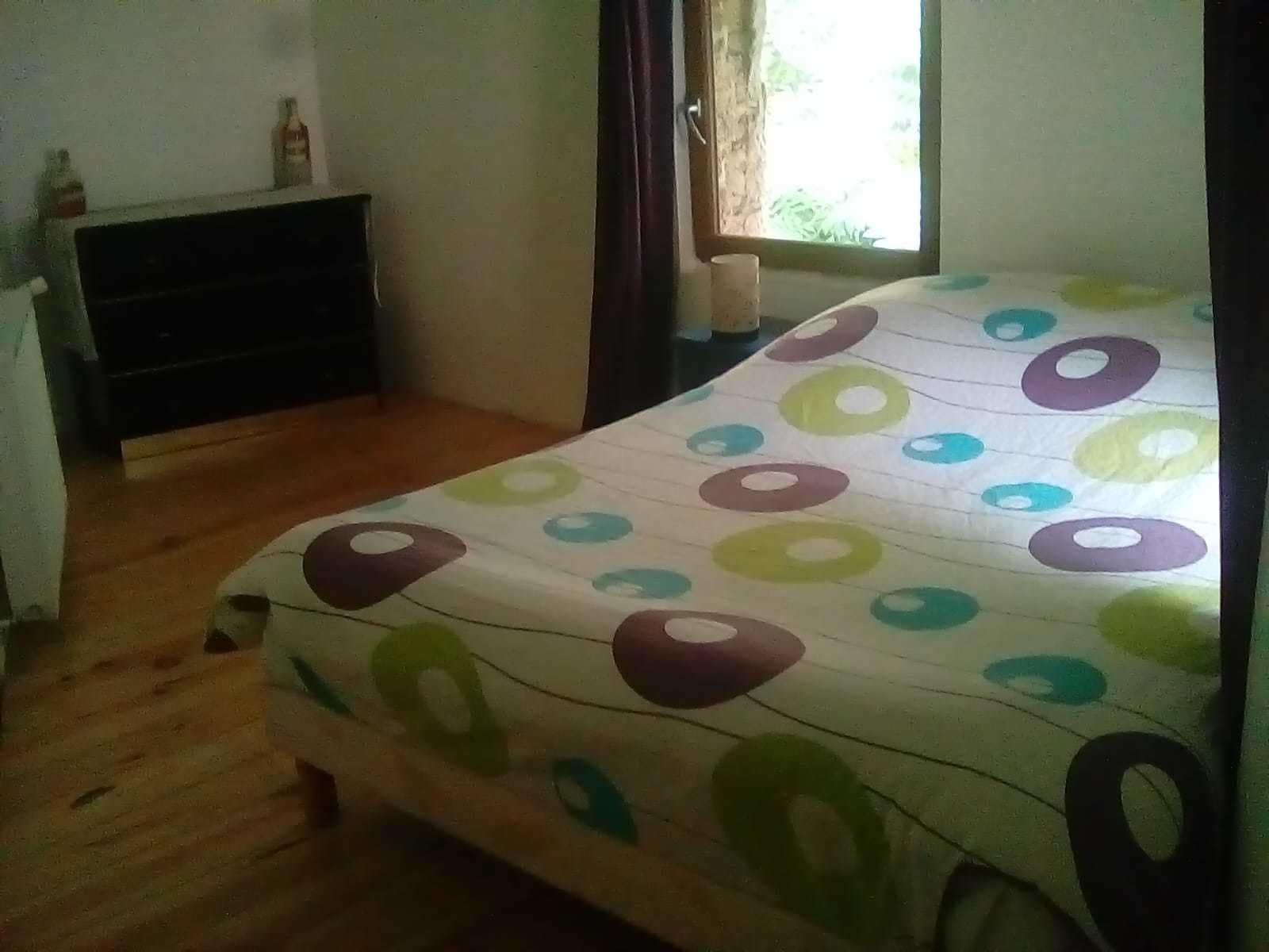 A bedroom with a bed, a dresser, a window, and a curtain.