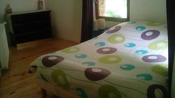 A bedroom with a bed, a dresser, a window, and a curtain.