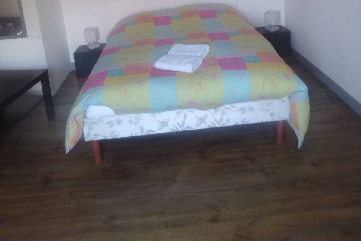 A room with a bed, a nightstand, a lamp, and a wall-mounted picture.