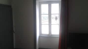 A room with a large window, a closed door, and a television on a stand.
