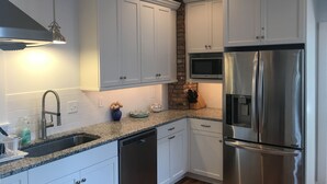 A modern kitchen with white cabinets, stainless steel appliances, a granite countertop, and a built-in microwave. - One Short Block to Beach - Spacious Victorian - 1st Floor Bed and Bath (Cape May)