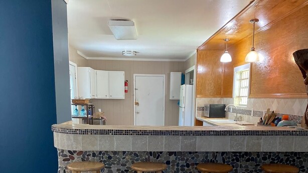 A kitchen with a tiled backsplash, wooden stools, and a wooden countertop. - Relax in Galveston, Texas! (Galveston)