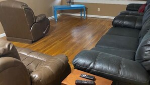 A living room with a brown leather sofa, a blue coffee table, and a TV mounted on the wall. - Relax in Galveston, Texas! (Galveston)