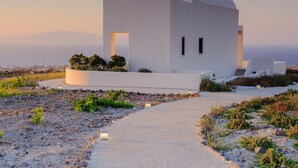 A white building with a curved roof, a small window, and a pathway leading to it. - Aplada Suites (Santorini)
