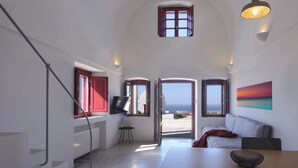 A modern interior with a sofa, a TV, and a painting. - Aplada Suites (Santorini)