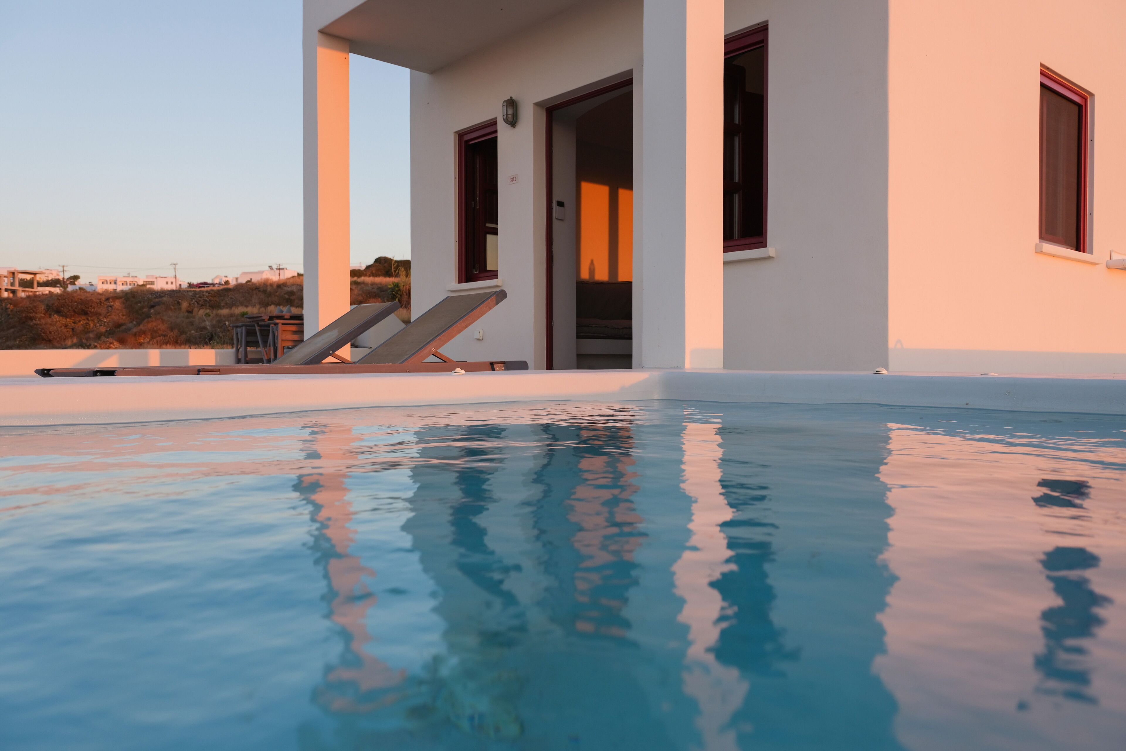 A modern pool area with clear water, a lounge chair, and a building with a door and windows.