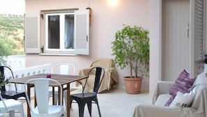 Un balcón con una mesa, sillas, una planta en maceta y un sofá.