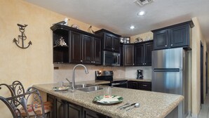 A kitchen with dark wooden cabinets, stainless steel appliances, and a granite countertop.