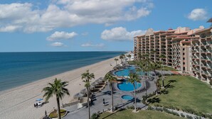 A resort with a pool area, beach access, and a large building with multiple balconies.