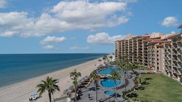 Ein Resort mit Poolbereich, Zugang zum Strand und einem großen Gebäude mit mehreren Balkonen.