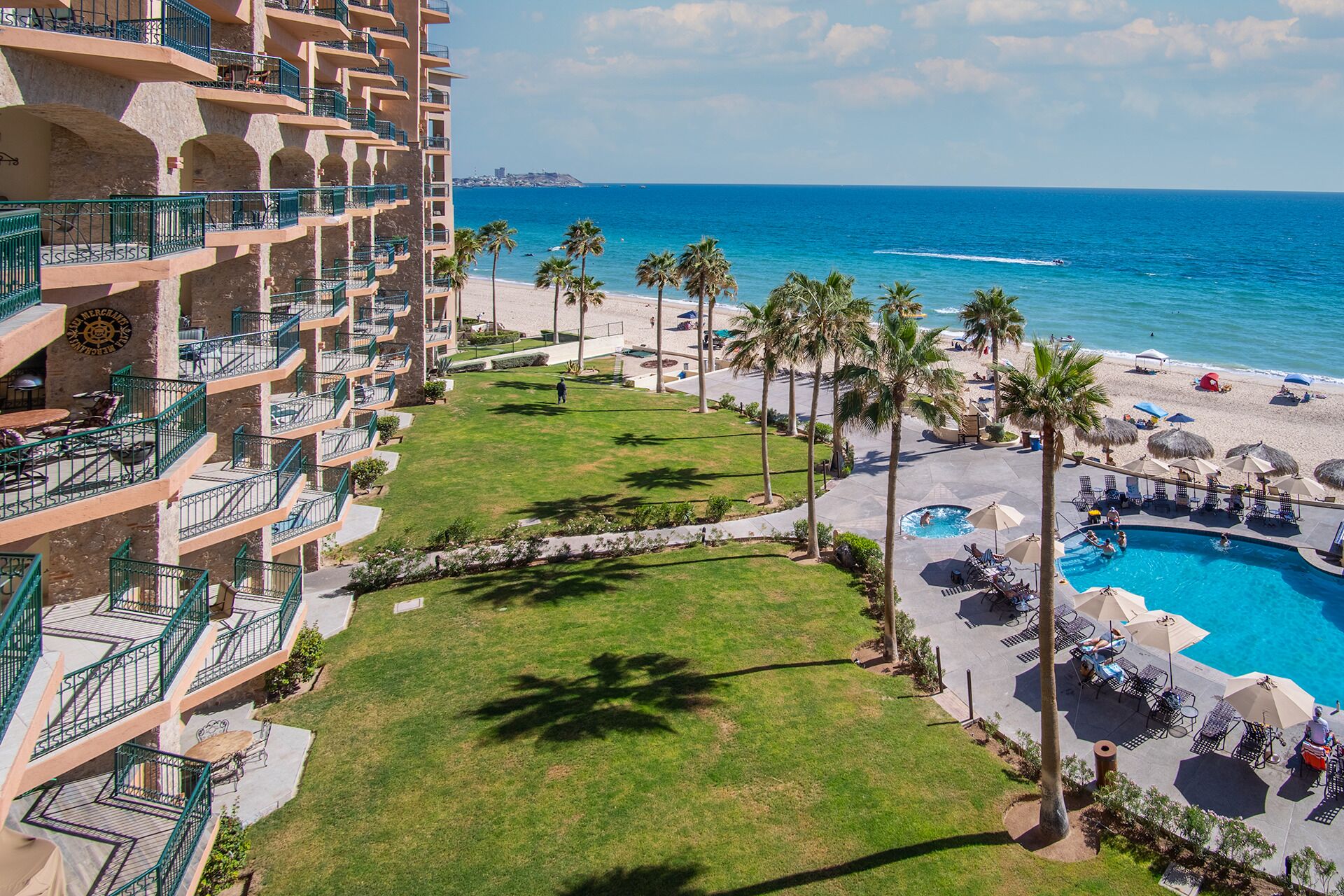 Un hôtel doté de nombreux balcons, d’un espace piscine et offrant une vue sur la plage.