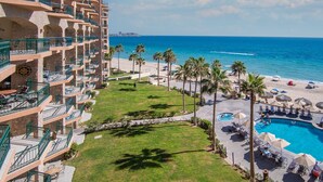 A hotel with multiple balconies, a pool area, and a beach view.