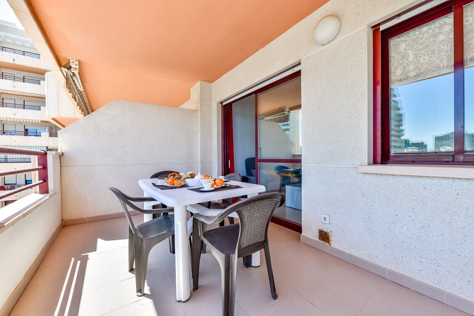 Un balcón con una mesa dispuesta para el desayuno, una silla y vistas del edificio de enfrente.
