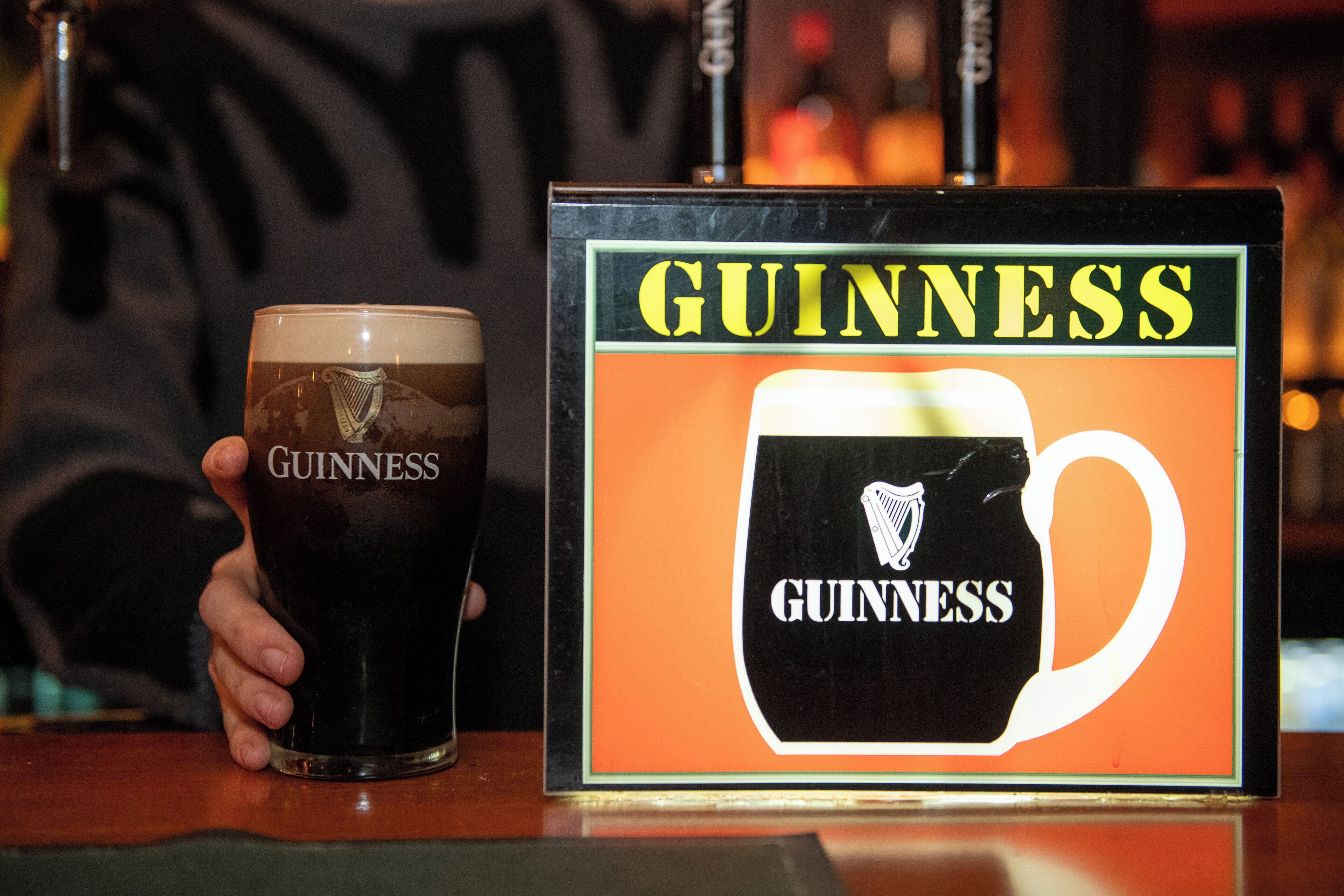 A Guinness glass and a branded coaster on a bar counter.