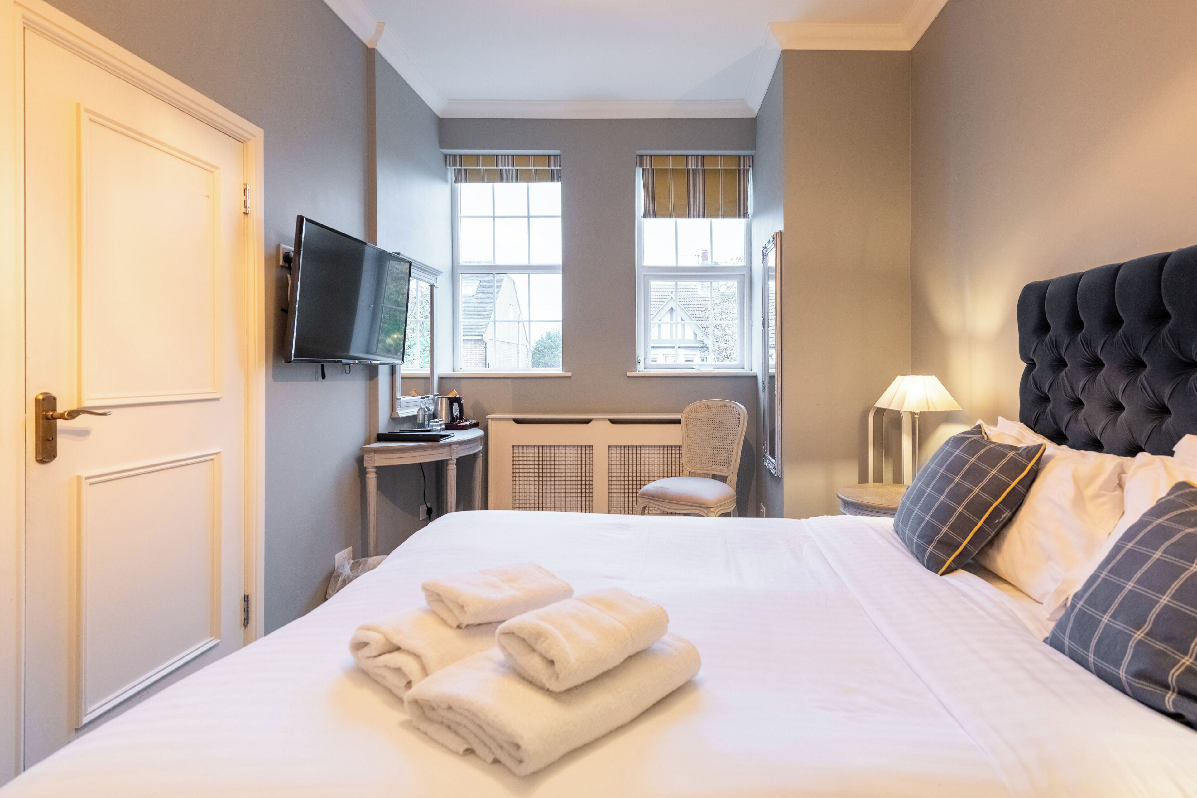 Ein Hotelzimmer mit Bett, Fernseher, Schreibtisch und Stuhl.