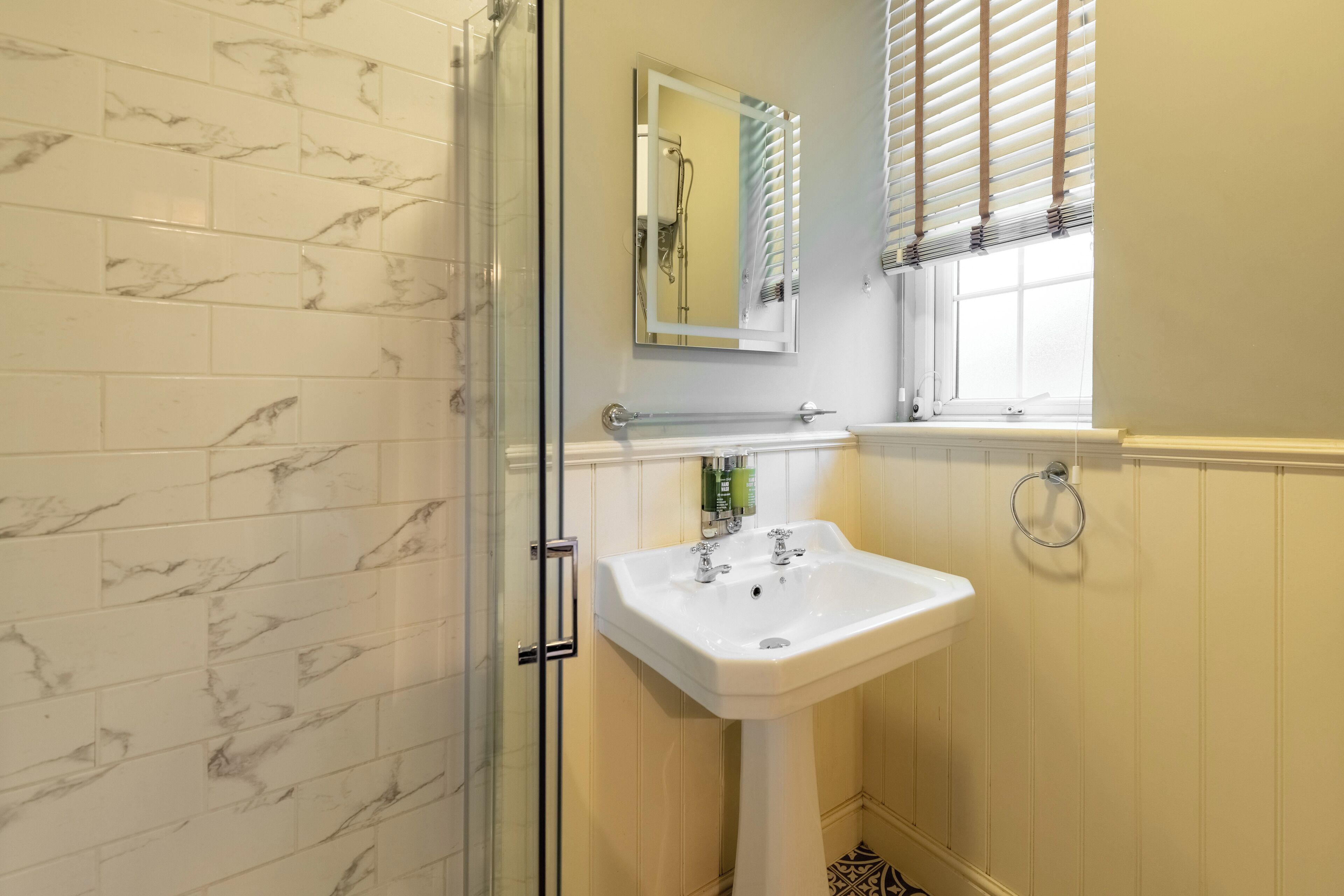 A bathroom with a glass shower enclosure, a white sink, and a mirror above it.