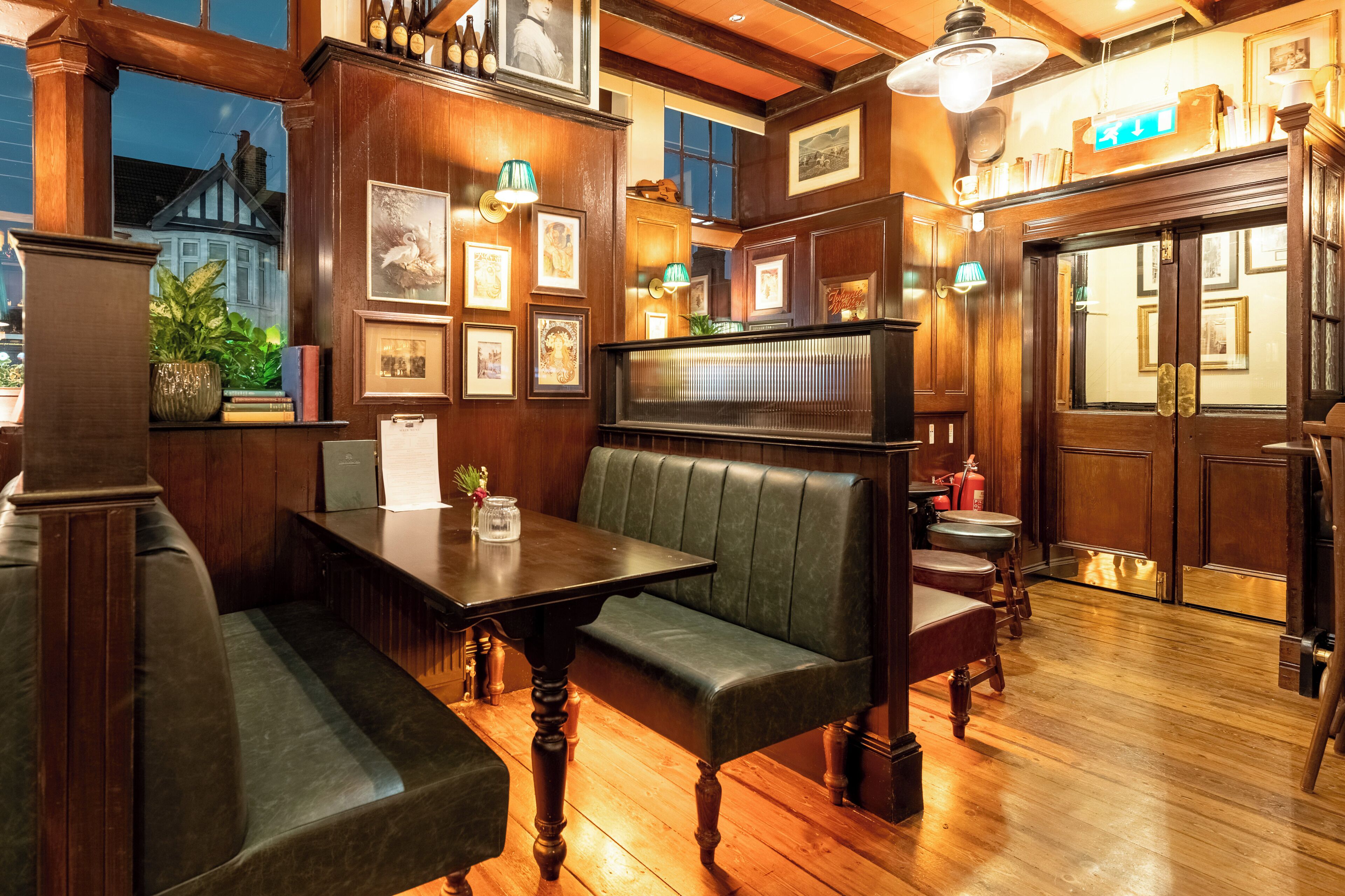 A cozy, wood-paneled room with a bench, a table, and framed pictures on the walls.